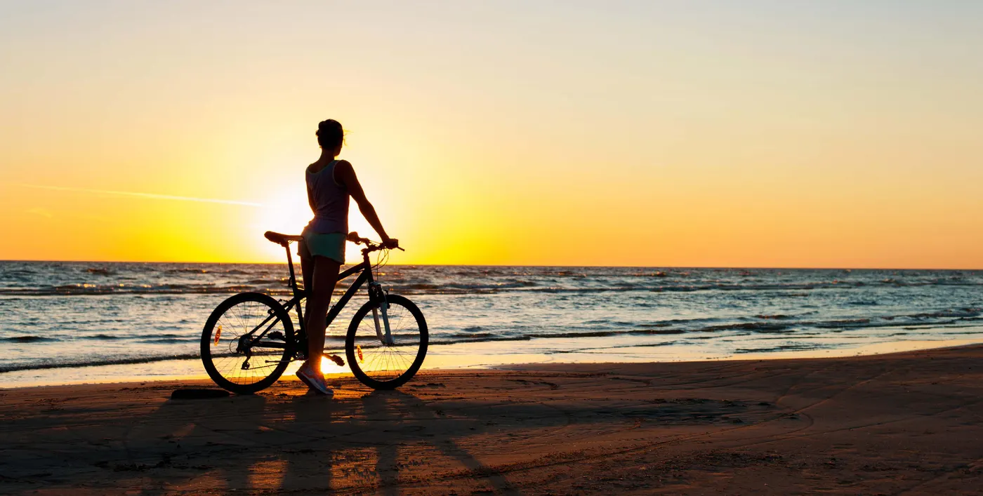 Passeio de bicicleta na praia ao entardecer